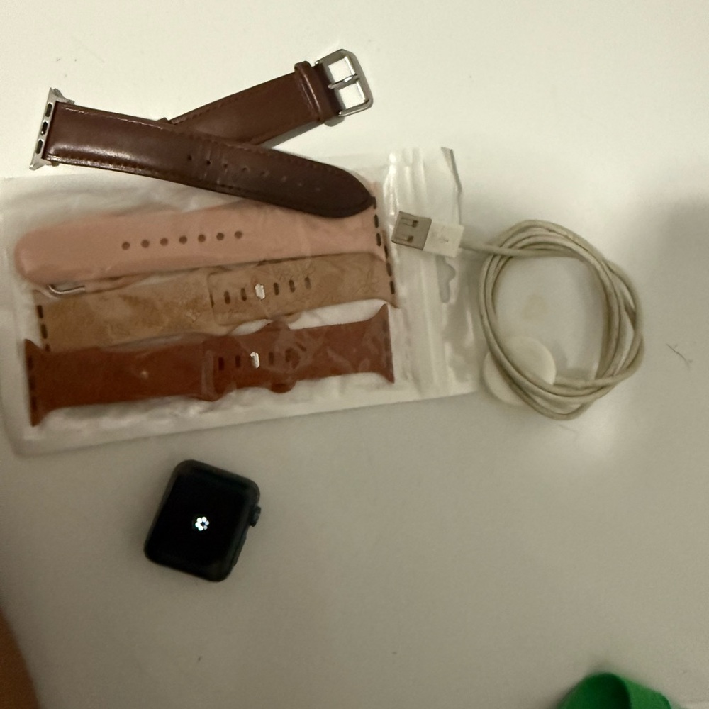 Apple Watch with Brown Leather and Pink Bands and White Charging Cable